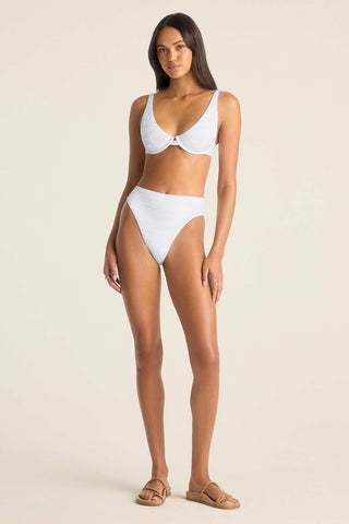 Woman wearing a white bikini top and matching high waisted white swim bottoms