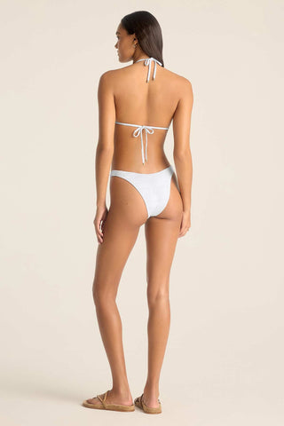Woman faced away wearing a white string bikini top and matching white swim bottoms
