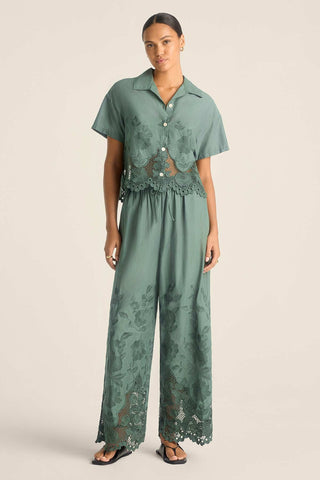Woman wearing a sea green lacy short sleeve beach shirt with matching pants